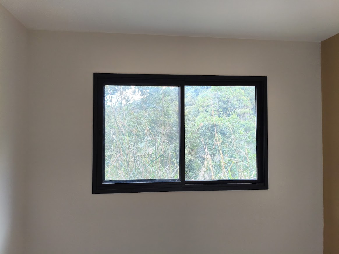 Janela preta de duas folhas com vista para a vegetação